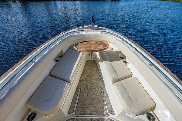 Slide: The Image of 2019 Chris-Craft Catalina 27 boat interior with cushioned seating and wooden table on calm water. - 11
