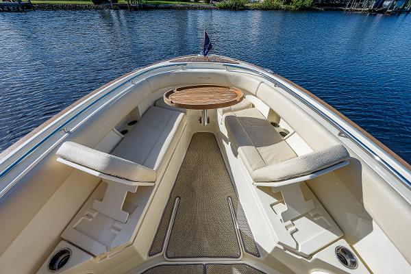 Slide: The Image of 2019 Chris-Craft Catalina 27 boat interior with cushioned seating and wooden table on calm water. - 12