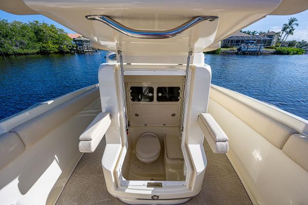 Slide: The Image of 2019 Chris-Craft Catalina 27 boat interior with open hatch and toilet, docked by a scenic waterfront. - 17