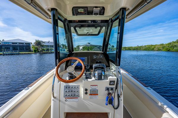 Slide: The Image of 2019 Chris-Craft Catalina 27 helm with wooden steering wheel, on a serene waterway. - 20