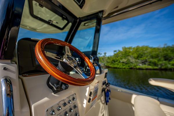 Slide: The Image of 2019 Chris-Craft Catalina 27 helm with wooden steering wheel, scenic waterway view. - 23