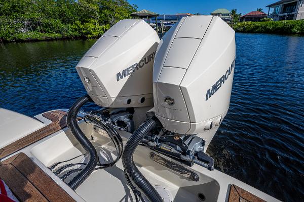 Slide: The Image of Twin Mercury outboard engines on a 2019 Chris-Craft Catalina 27 boat, docked by lush greenery. - 33