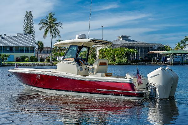 Slide: The Image of 2019 Chris-Craft Catalina 27 boat with red hull on calm water, palm trees in background. - 5