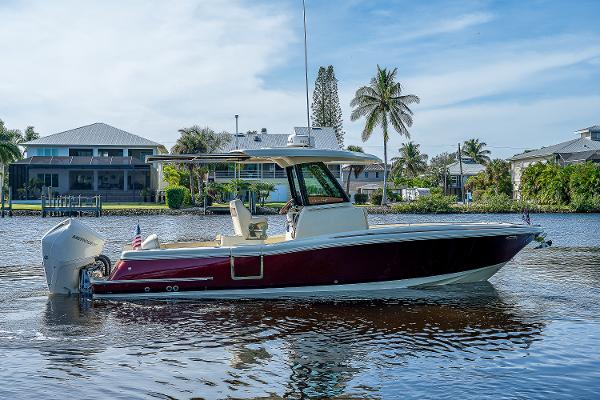 Slide: The Image of 2019 Chris-Craft Catalina 27 boat on a sunny waterfront, with palm trees and houses in the background. - 8