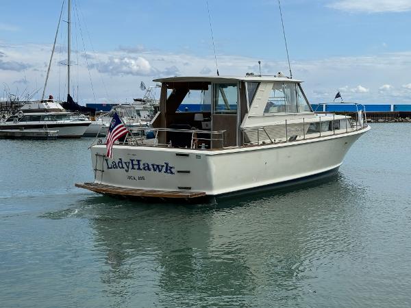 Slide: The Image of 1969 Chris-Craft Commander boat named LadyHawk on calm water, displaying an American flag. - 13