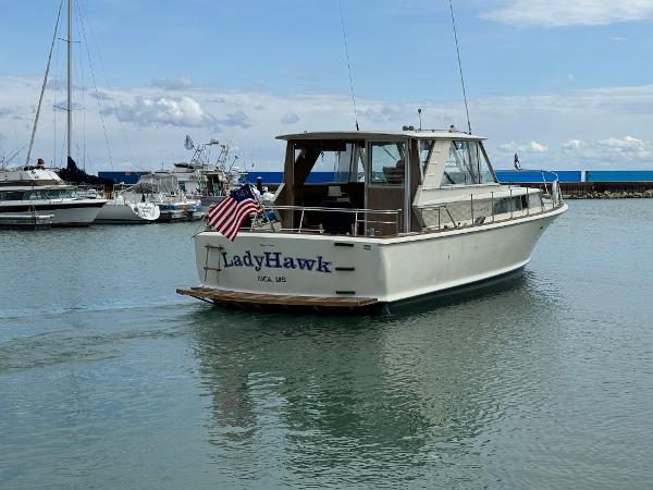 Slide: The Image of 1969 Chris-Craft Commander boat named "LadyHawk" in a marina, displaying an American flag. - 14