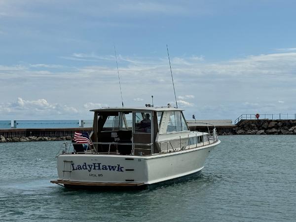 Slide: The Image of 1969 Chris-Craft Commander boat named LadyHawk on calm water near a pier. - 19