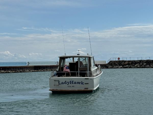 Slide: The Image of 1969 Chris-Craft Commander boat "LadyHawk" cruising on a calm lake near a rocky pier. - 20