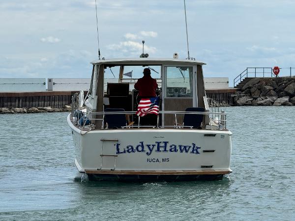Slide: The Image of 1969 Chris-Craft Commander boat "LadyHawk" on water, rear view with American flag. - 21