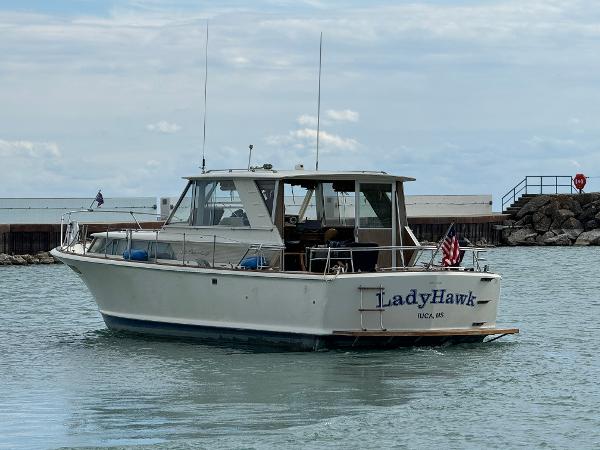 Slide: The Image of 1969 Chris-Craft Commander boat named "LadyHawk" on calm water near a rocky shore. - 23