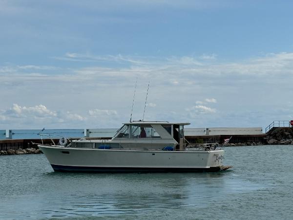 Slide: The Image of 1969 Chris-Craft Commander boat on calm water near a pier under a cloudy sky. - 25