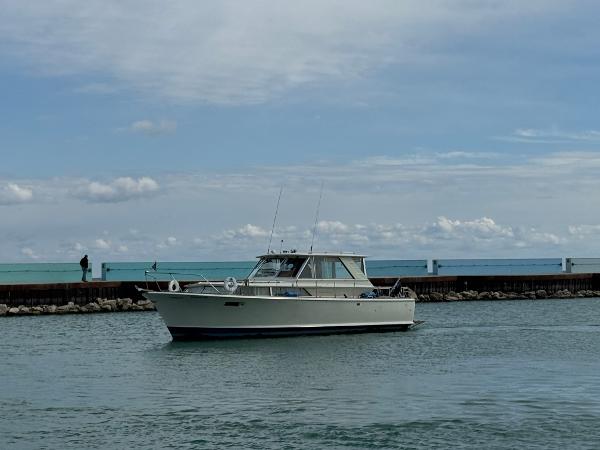 Slide: The Image of 1969 Chris-Craft Commander boat on calm water near a pier under a cloudy sky. - 29