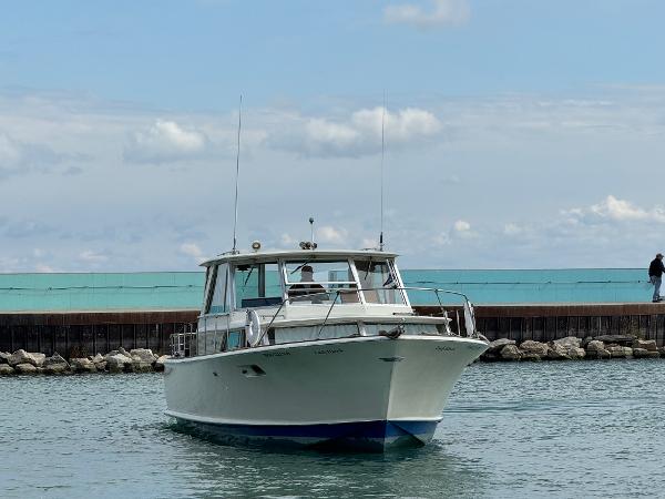 Slide: The Image of 1969 Chris-Craft Commander boat on water near a rocky shoreline under a cloudy sky. - 33