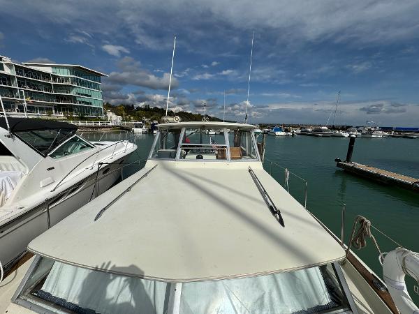 Slide: The Image of 1969 Chris-Craft Commander docked at marina, under a partly cloudy sky. - 39