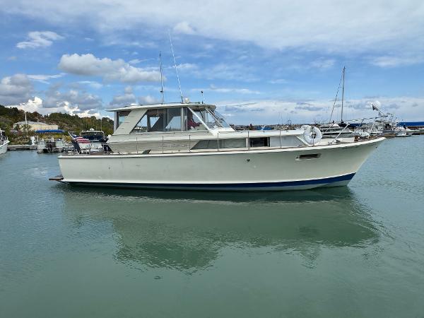 Slide: The Image of 1969 Chris-Craft Commander boat docked on calm water under a partly cloudy sky. - 8