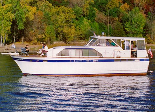 Slide: The Image of 1964 Chris-Craft Constellation boat cruising on a lake with lush green trees in the background. - 0