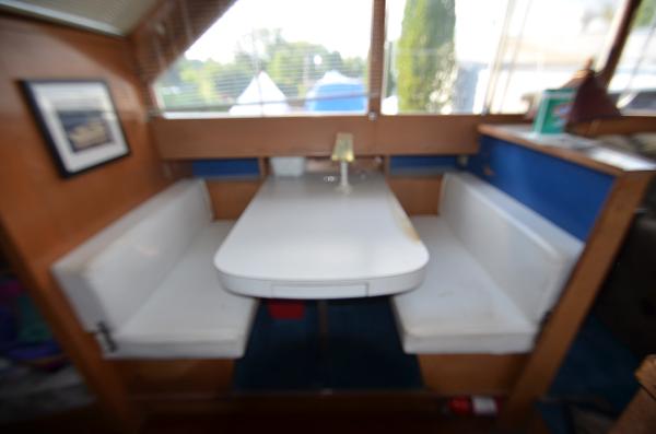 Slide: The Image of 1964 Chris-Craft Constellation interior dining area with white cushioned seating. - 12