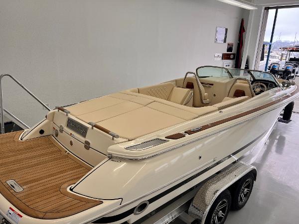 Slide: The Image of 2023 Chris-Craft Launch 27 boat with beige interior and wooden deck on a trailer. - 1