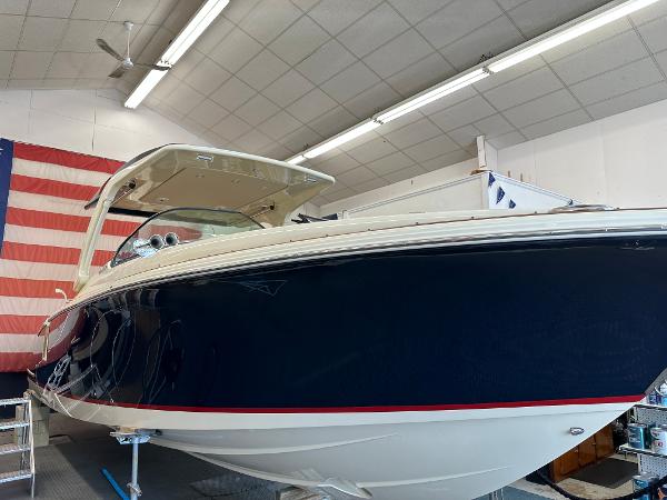 Slide: The Image of 2024 Chris-Craft Launch 31 GT boat in a showroom with an American flag. - 0
