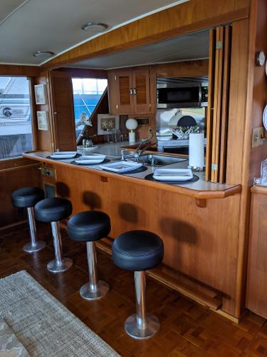 Slide: The Image of 1976 Chris-Craft Roamer yacht interior with bar stools and kitchen area. - 14