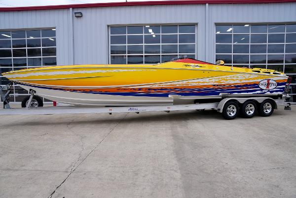 Slide: The Image of 2005 Cigarette 38 Top Gun speedboat in yellow, orange, and blue on a trailer. - 0