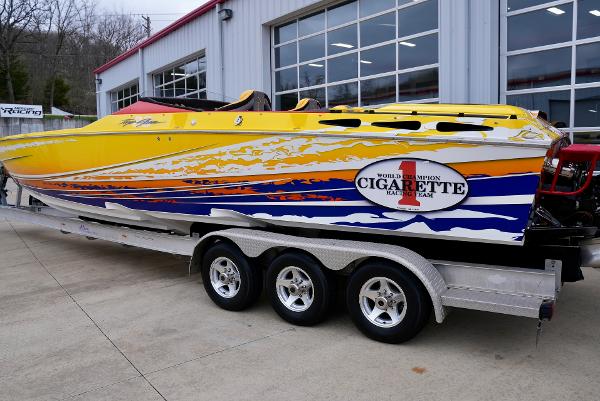 Slide: The Image of 2005 Cigarette 38 Top Gun speedboat with vibrant yellow, orange, and blue graphics on a trailer. - 2
