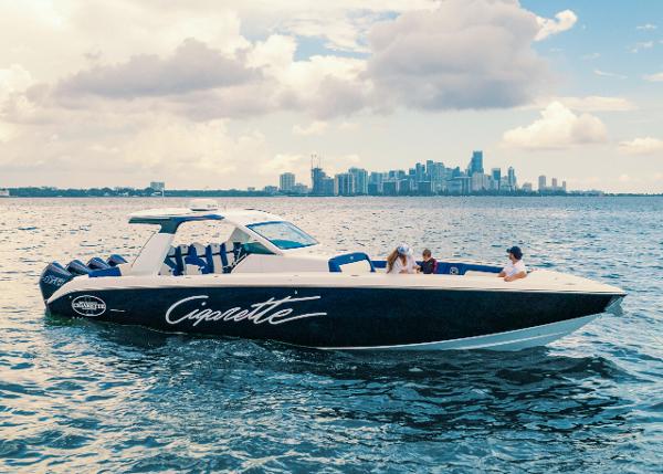 Slide: The Image of 2025 Cigarette 41 Nighthawk boat cruising on water with city skyline in background. - 2