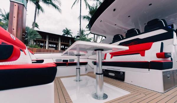 Slide: The Image of 2024 Cigarette 52 Thunder boat interior with red and black seating, table, and tropical background. - 9