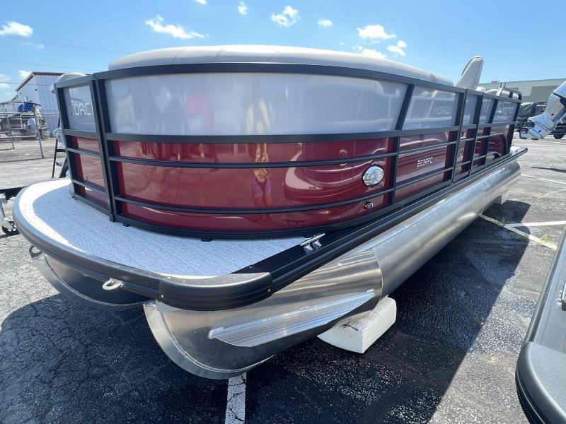 Slide: The Image of 2023 Coach 223 RFC pontoon boat with red and silver exterior, docked on pavement. - 1