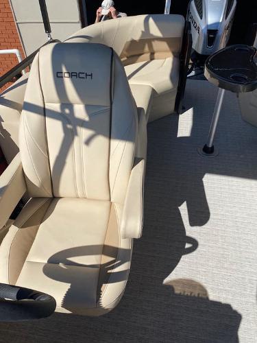 Slide: The Image of 2023 Coach Pontoons 223RFC boat interior with beige seating and steering wheel. - 4