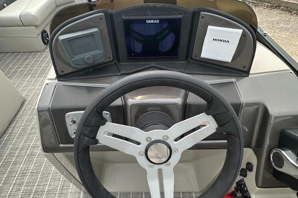 Slide: The Image of 2023 Coach Pontoons 243PFC dashboard with steering wheel and Simrad display. - 5