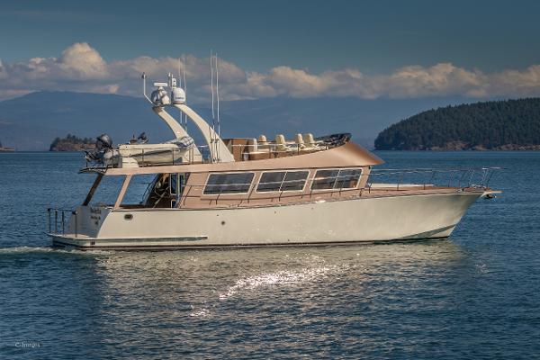 Slide: The Image of 2012 Coastal Craft 56 yacht cruising on serene waters with scenic island backdrop. - 0
