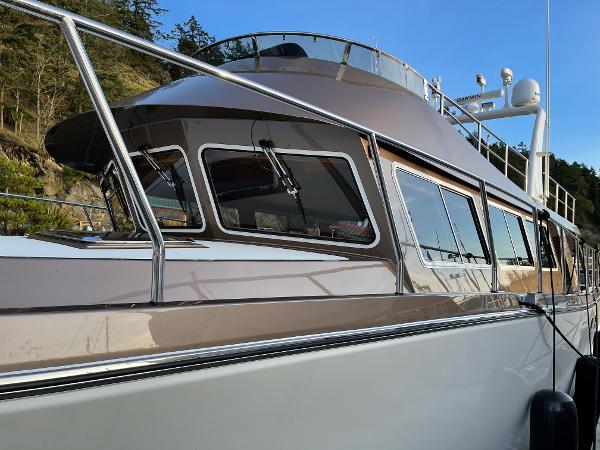 Slide: The Image of 2012 Coastal Craft 56 yacht with sleek design and modern windows, docked by a forested shoreline. - 18