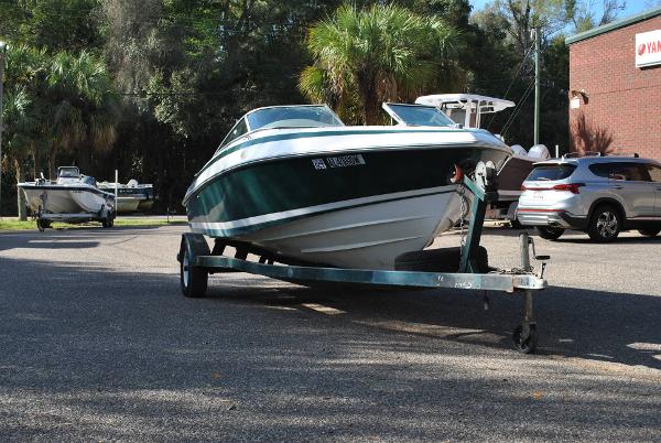 Slide: The Image of 1998 Cobalt 200 boat on trailer in parking lot, surrounded by trees and vehicles. - 20
