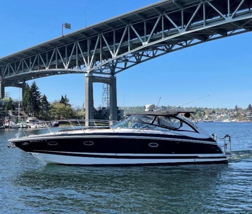 Slide: The Image of 2004 Cobalt 360 boat cruising under a large bridge on a sunny day. - 0