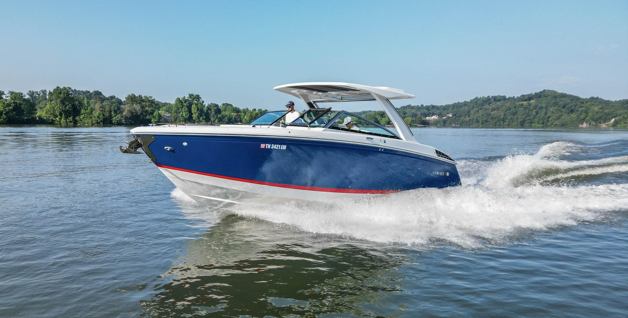 Slide: The Image of 2023 Cobalt R33 boat cruising on a scenic lake with lush green hills. - 0