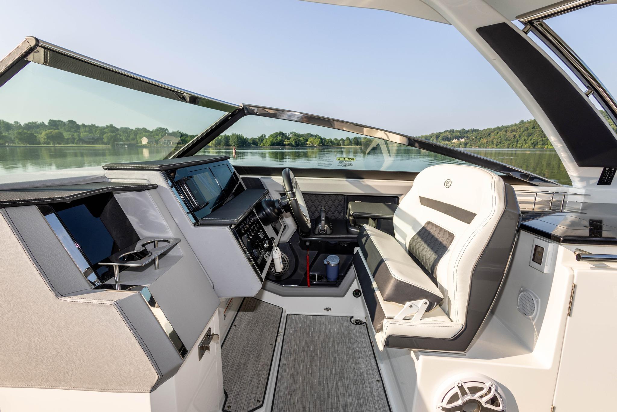 Slide: The Image of 2023 Cobalt R33 boat cockpit with modern controls and luxurious seating on a serene lake. - 16