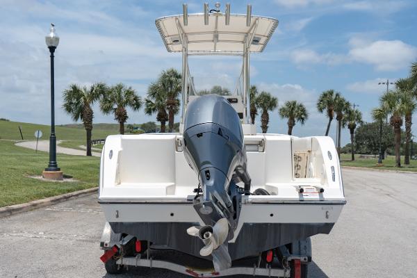 Slide: The Image of 2021 Cobia 201 Center Console boat on trailer, rear view with outboard motor, palm trees in background. - 7