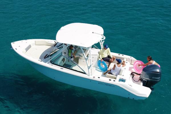 Slide: The Image of Manufacturer Provided Image: 2023 Cobia 240 Dual Console boat on clear blue water with passengers. - 1