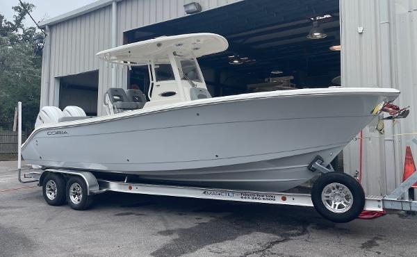Slide: The Image of 2024 Cobia 262 Center Console boat on a trailer outside a warehouse. - 0