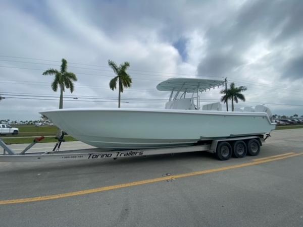 Slide: The Image of 2025 Contender 35 ST boat on trailer, parked roadside with palm trees. - 0