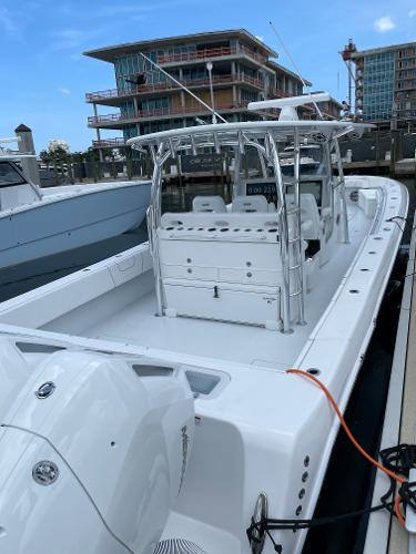Slide: The Image of 2025 Contender 44ST boat docked at a marina with modern buildings in the background. - 19