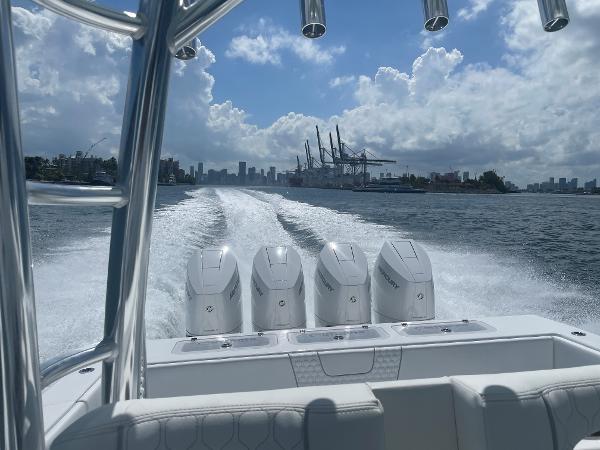 Slide: The Image of Contender 2025 44ST boat with quad engines cruising on water, city skyline in background. - 5