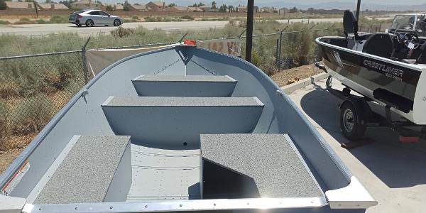 Slide: The Image of 2023 Crestliner 1469 Outreach boat, parked outdoors, showcasing interior seating and design. - 2
