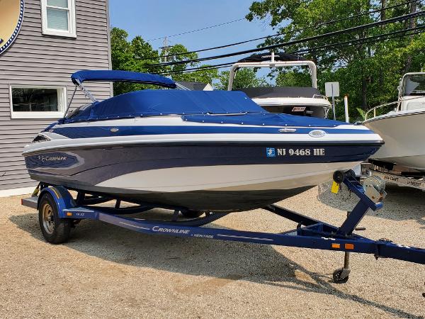 Slide: The Image of 2013 Crownline 19XS boat on a trailer, blue and white, parked outdoors. - 1