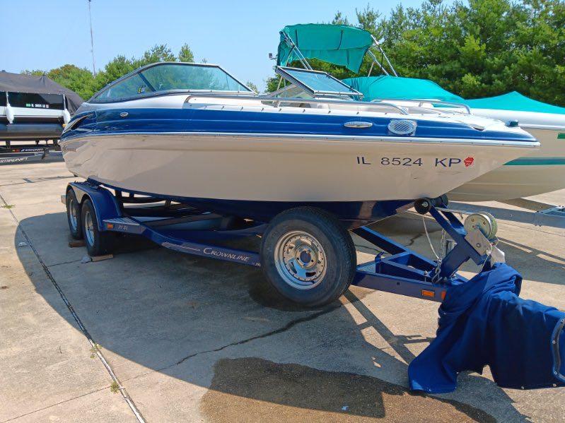 Slide: The Image of 2012 Crownline 21SS boat on a trailer, blue and white, parked outdoors. - 1