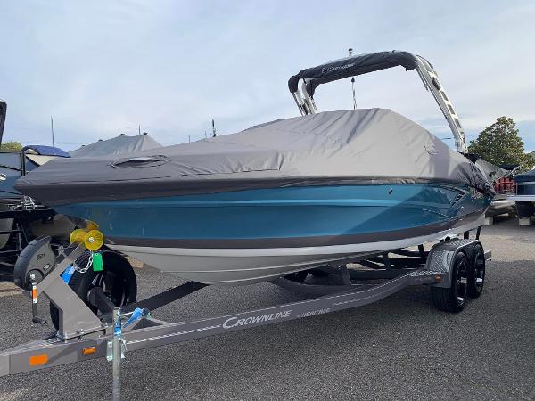 Slide: The Image of 2024 Crownline 240SS boat on trailer with cover, blue hull, and black bimini top. - 0