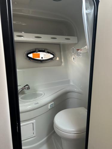Slide: The Image of 2024 Crownline 270 CR boat bathroom with sink, toilet, and porthole window. - 17