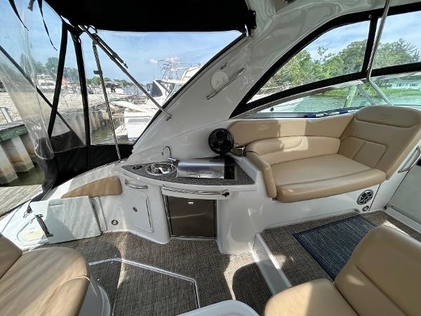 Slide: The Image of 2015 Crownline 350 SY yacht interior with seating, kitchenette, and windows overlooking marina. - 23