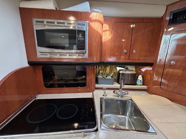 Slide: The Image of 2015 Crownline 350 SY yacht kitchen with microwave, stove, and sink. - 8